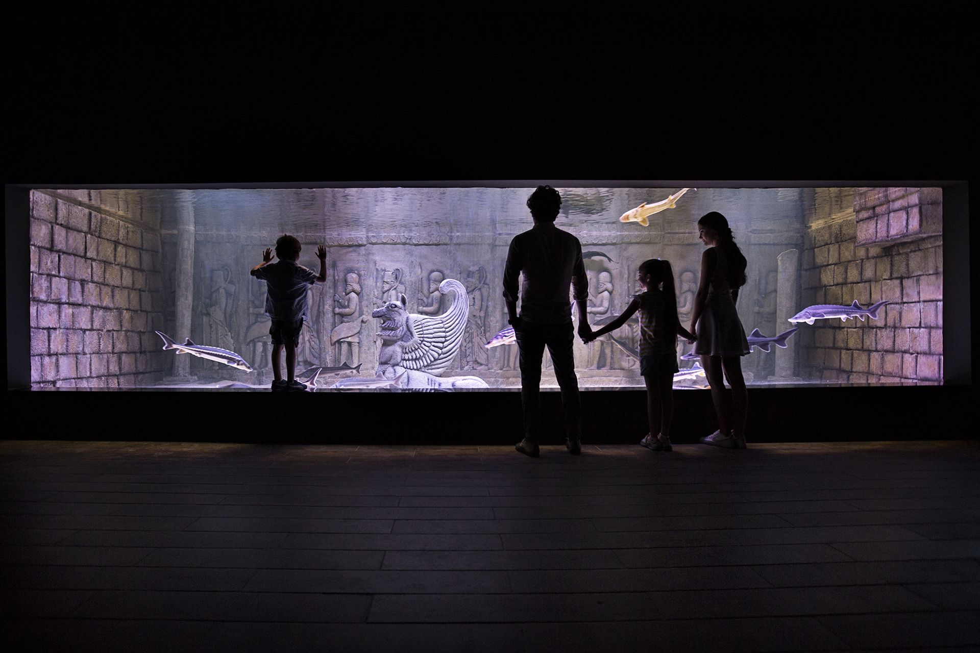 Family at the Mesopotamian-themed sturgeon tank with carved reliefs at Via Sea Aquarium, Istanbul